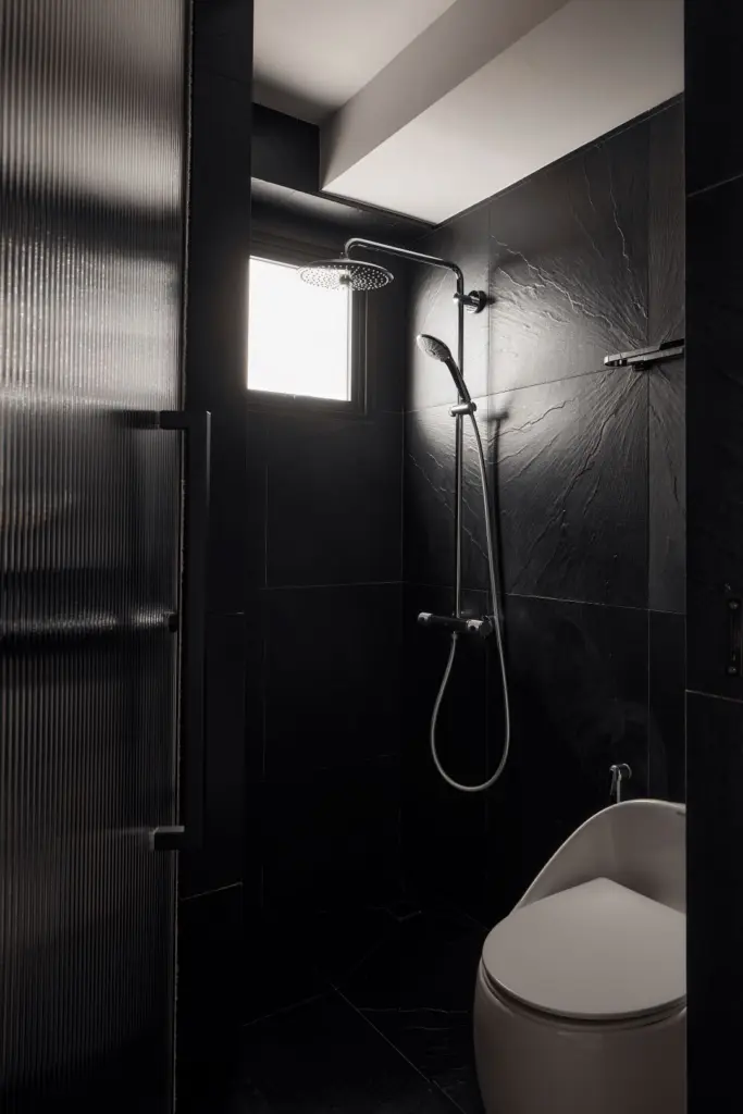 Modern bathroom with black tiles and shower.