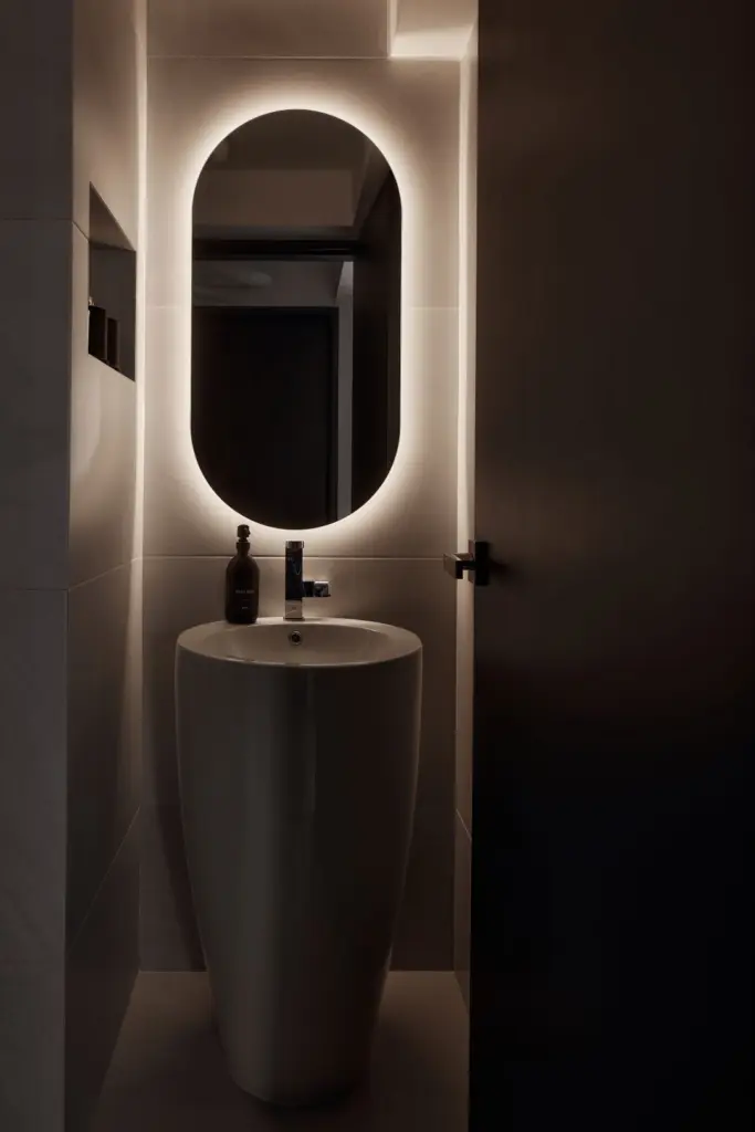 Modern bathroom with illuminated mirror and sink.