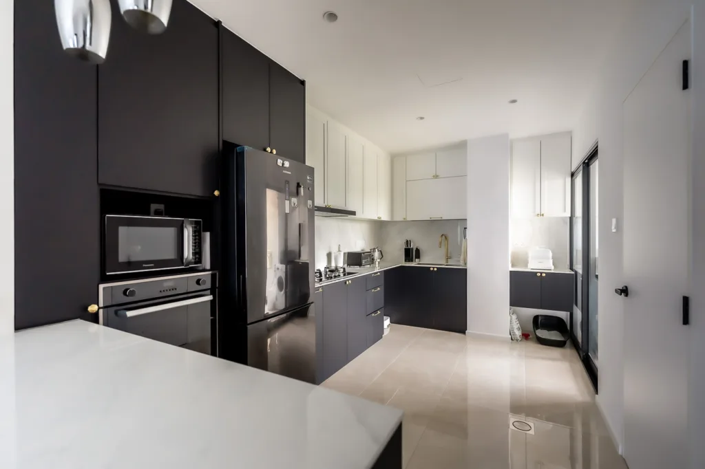 Modern kitchen with black cabinets and white countertops.