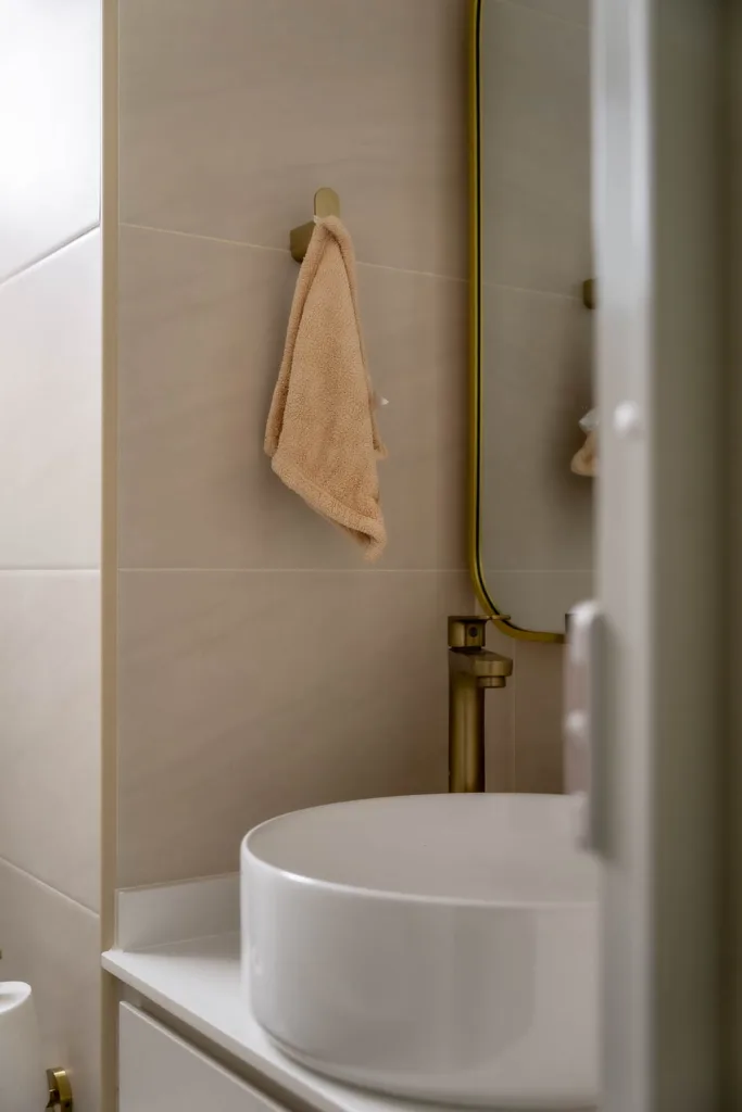 Modern bathroom interior with round sink and beige towel.