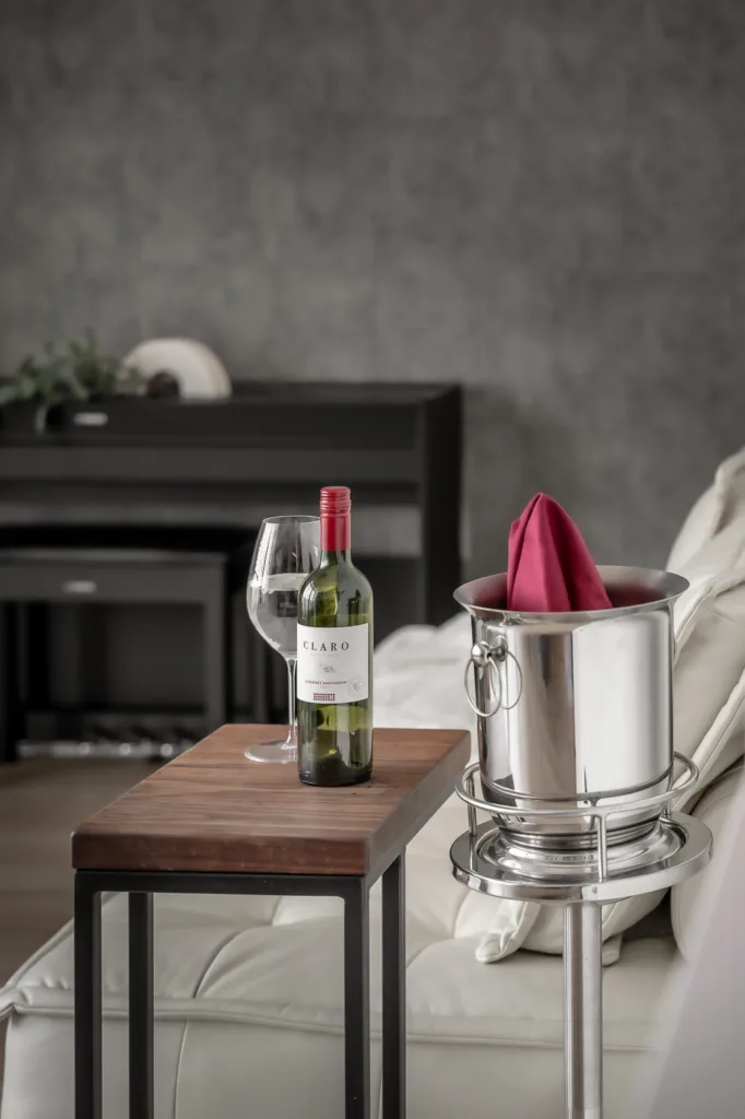 Wine bottle and glass on nightstand with ice bucket.
