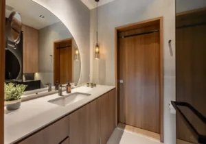 Modern bathroom interior with wooden accents and oval mirror.