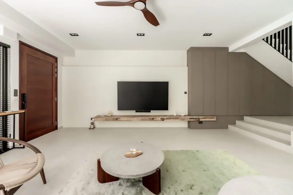 Modern living room with large TV and minimalist furniture.