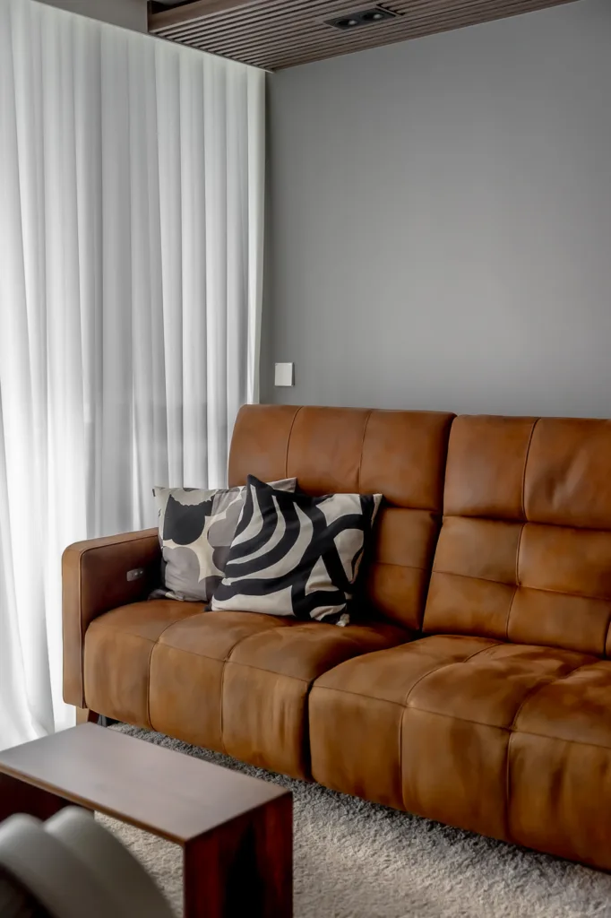 Modern brown leather couch with decorative pillows.