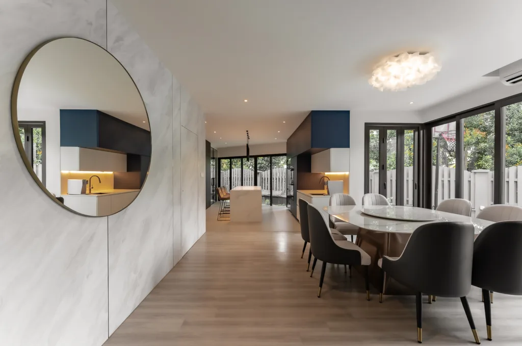 Modern dining room with circular mirror and designer lighting.