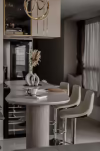 Modern kitchen island with marble countertop, bar stools, and dried floral arrangement.