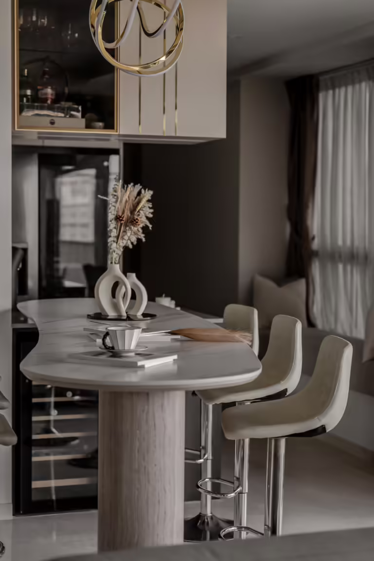 Modern kitchen island with marble countertop, bar stools, and dried floral arrangement.