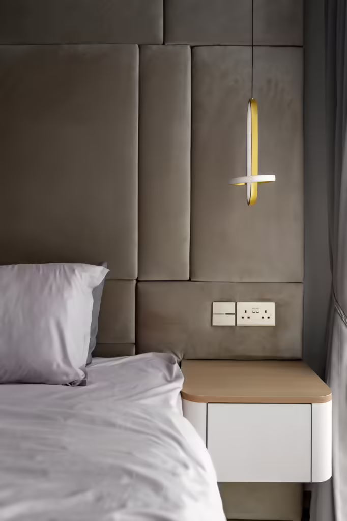 Modern bedroom at 24 Sumang Walk, featuring a grey headboard, bedside table, and pendant light.