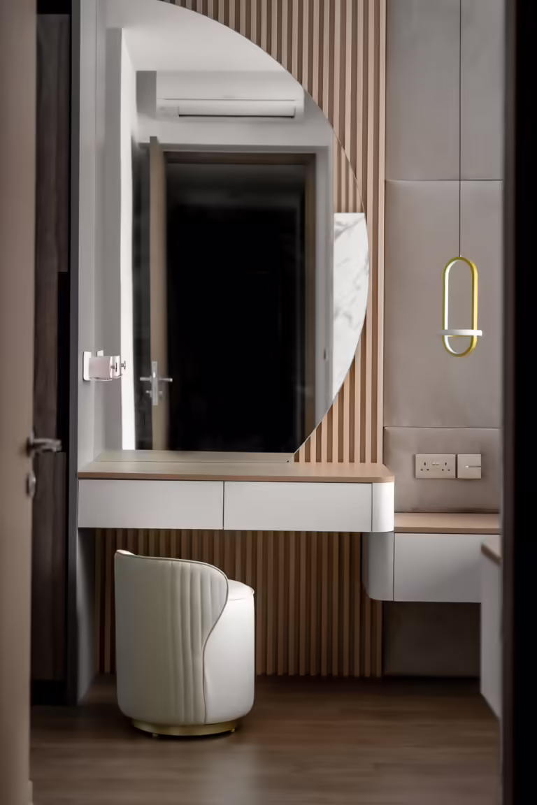 Modern vanity with curved mirror and upholstered stool at 24 Sumang Walk.