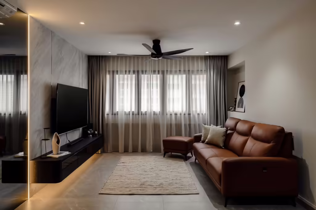 Modern living room in a 704 Tampines HDB flat, featuring a brown leather sofa and large TV.