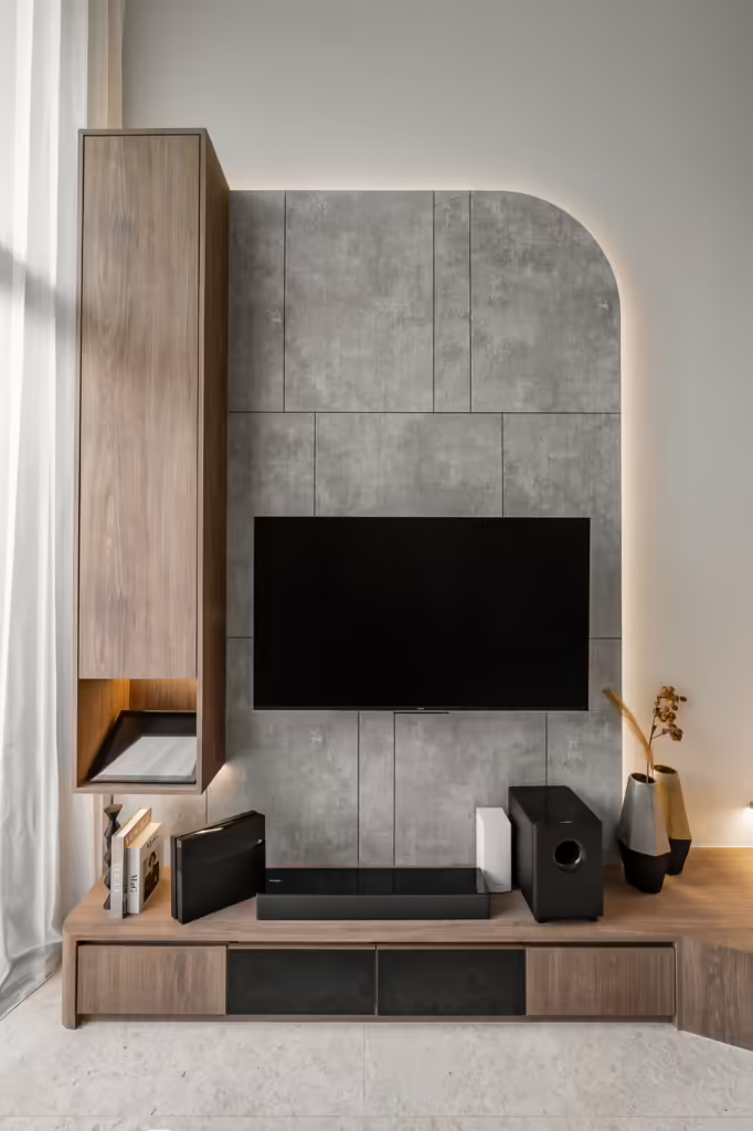 Modern living room with wood and concrete wall features, TV, and entertainment center.