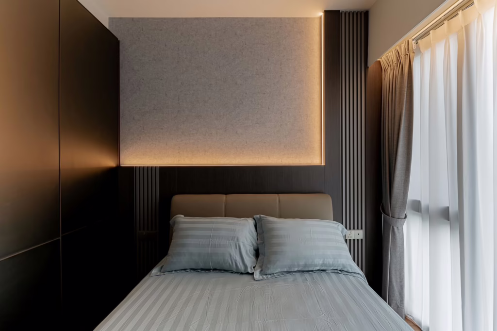 Modern bedroom with gray bedding, dark wood accents, and soft lighting.