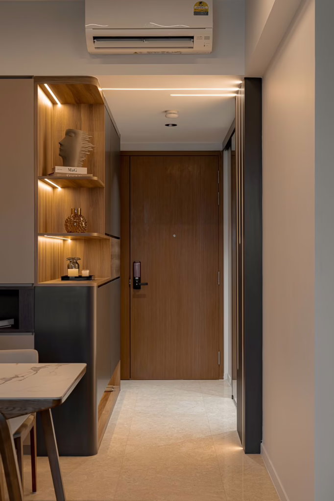 Modern apartment entryway with wood and dark gray cabinetry, marble table, and warm lighting.
