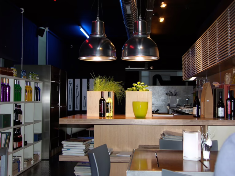 Modern restaurant interior with wine bottles, industrial lighting, and wooden bar