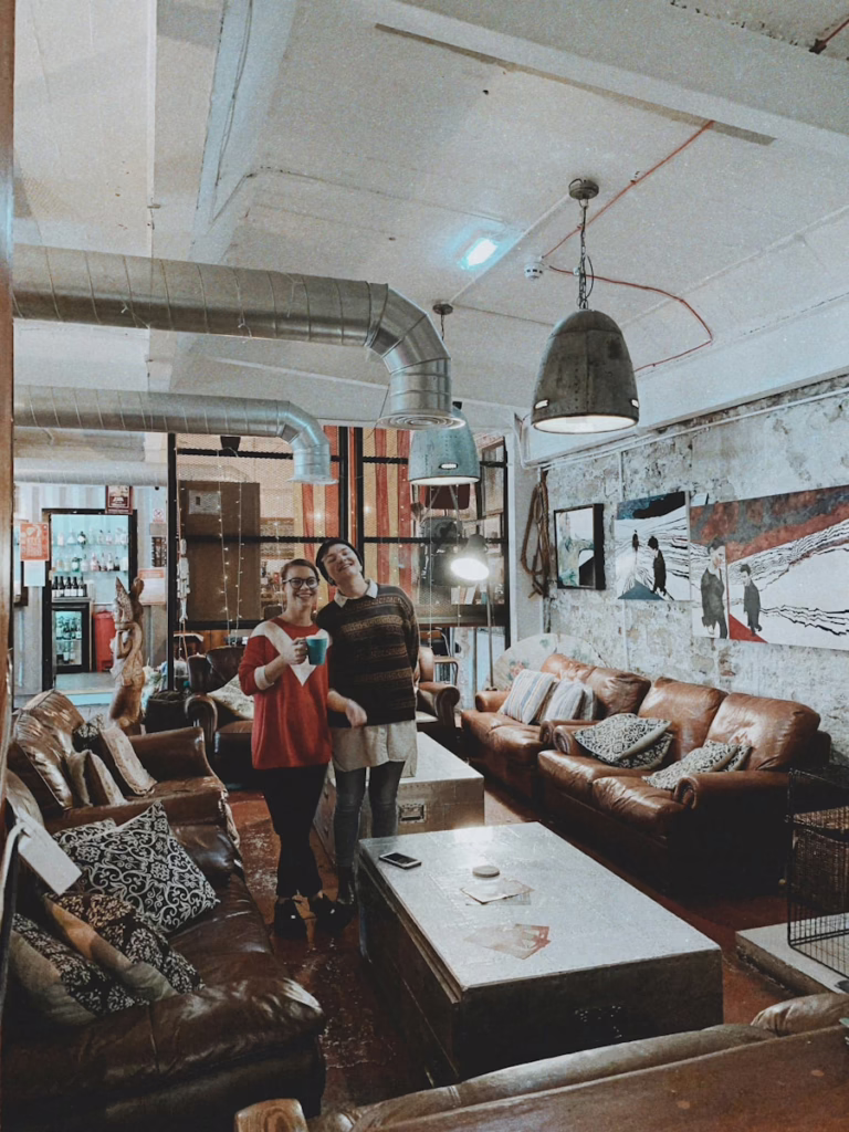 Two friends enjoy coffee in a cozy, industrial-style cafe.