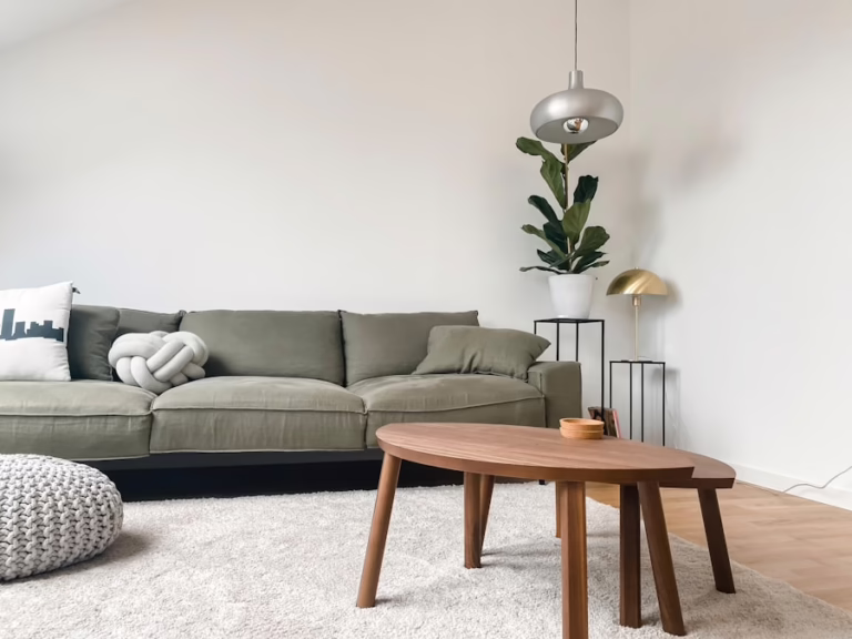 Modern living room with olive green sofa, wooden coffee table, and fiddle leaf fig plant.
