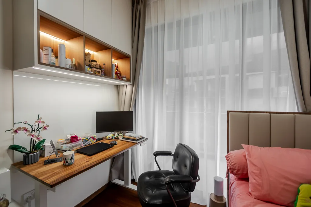Modern home office with wooden desk, black chair, and built-in shelving.