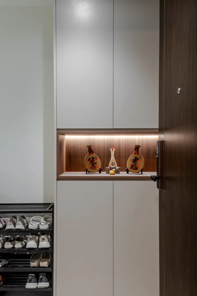 Modern entryway with built-in shoe storage, cabinet, and decorative display shelf.