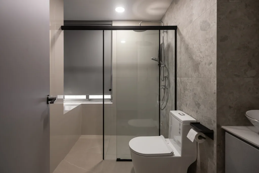 Modern bathroom with glass shower, toilet, and gray marble tile