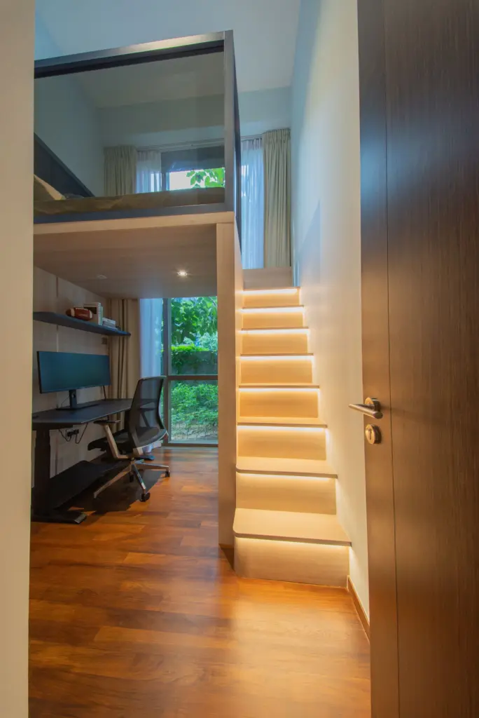Modern loft with cozy workspace and staircase.
