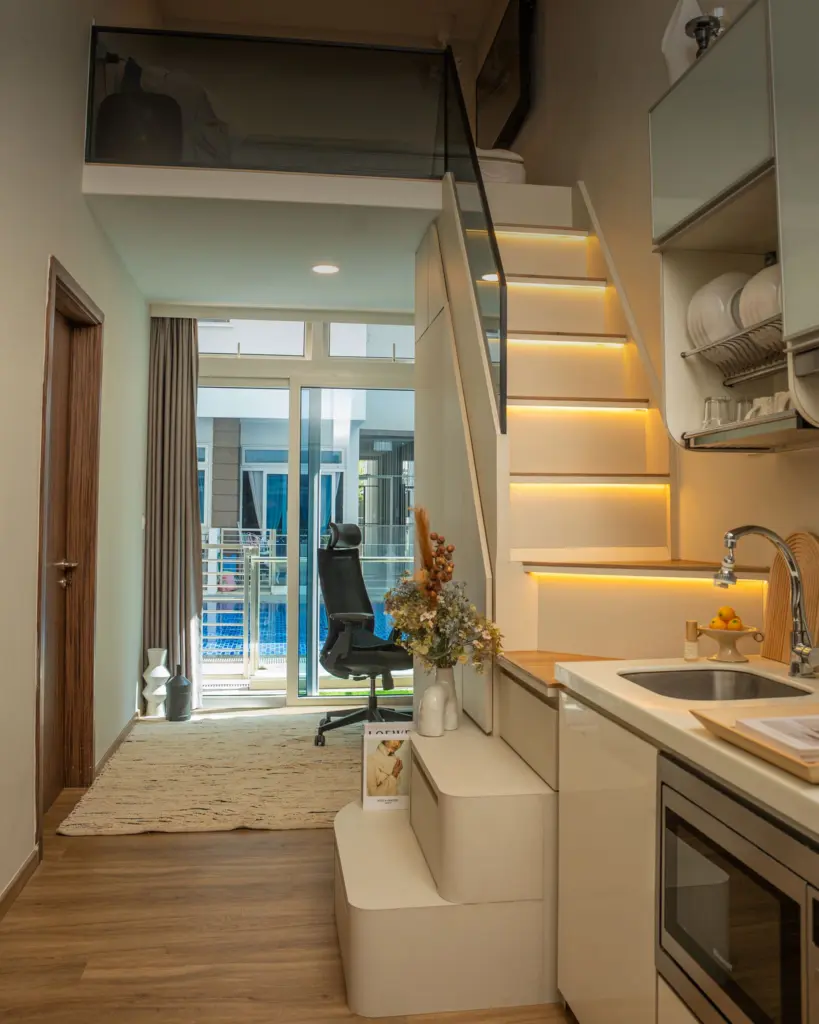 Compact mezzanine loft with lit staircase and integrated kitchen at Suites @ East Coast by IS Design Studio