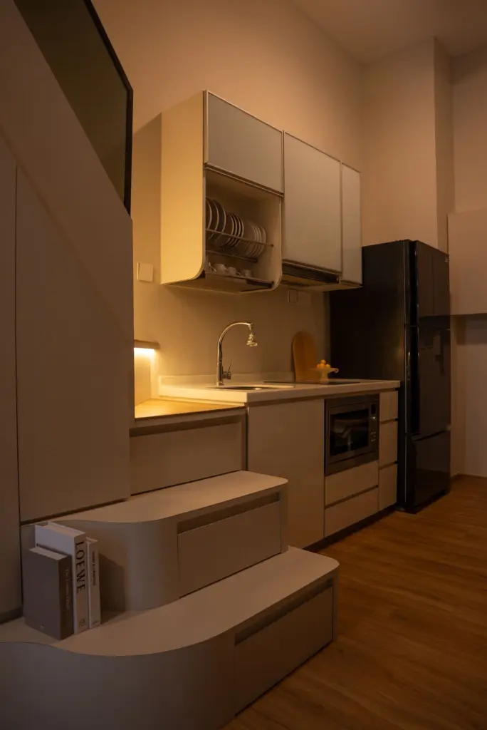 Modern kitchen with sleek cabinets and black refrigerator. — at Suites @ East Coast, a loft interior by IS Design Studio