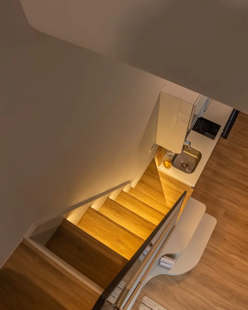 Spiral staircase with wooden steps and kitchen view. — at Suites @ East Coast, a loft interior by IS Design Studio