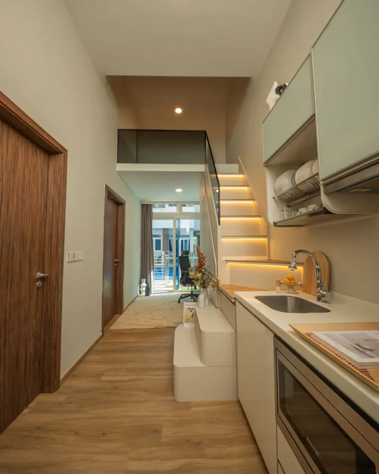 Modern kitchen with wooden floor and staircase.
