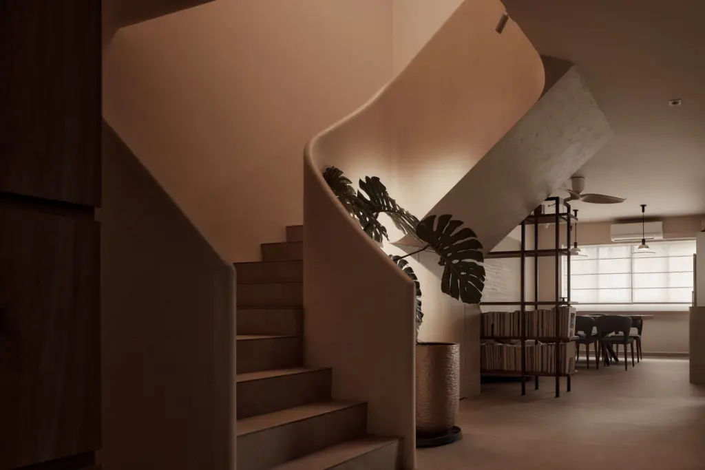 Modern minimalist staircase with curved concrete wall and large plant — at Kim Keat Avenue, an HDB executive maisonette by IS Design Studio