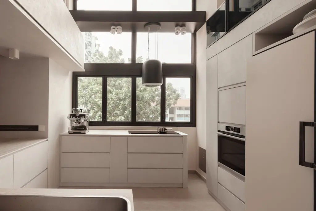 Modern kitchen with large windows and sleek design. — at Kim Keat Avenue, an HDB executive maisonette by IS Design Studio