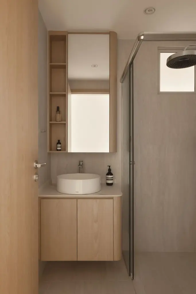 Minimalist bathroom with wooden cabinets and glass shower.